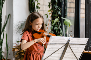 Girl reading music notes and playing violin.