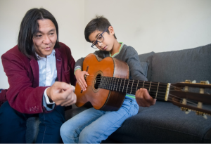 Man teaching a child to play the guitar.