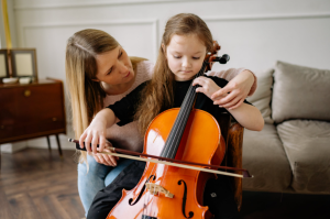Woman teaching girl to play the cello.