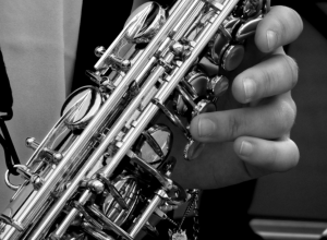 Grayscale photo of person holding a saxophone.