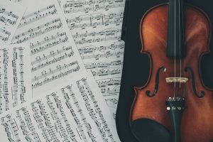 Brown violin with a case kept on music notes 