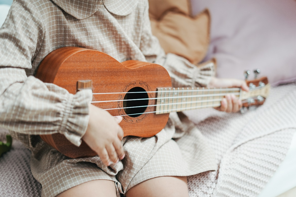 A toddler playing the ukulele
