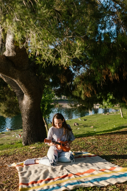 A woman playing ukulele in a park