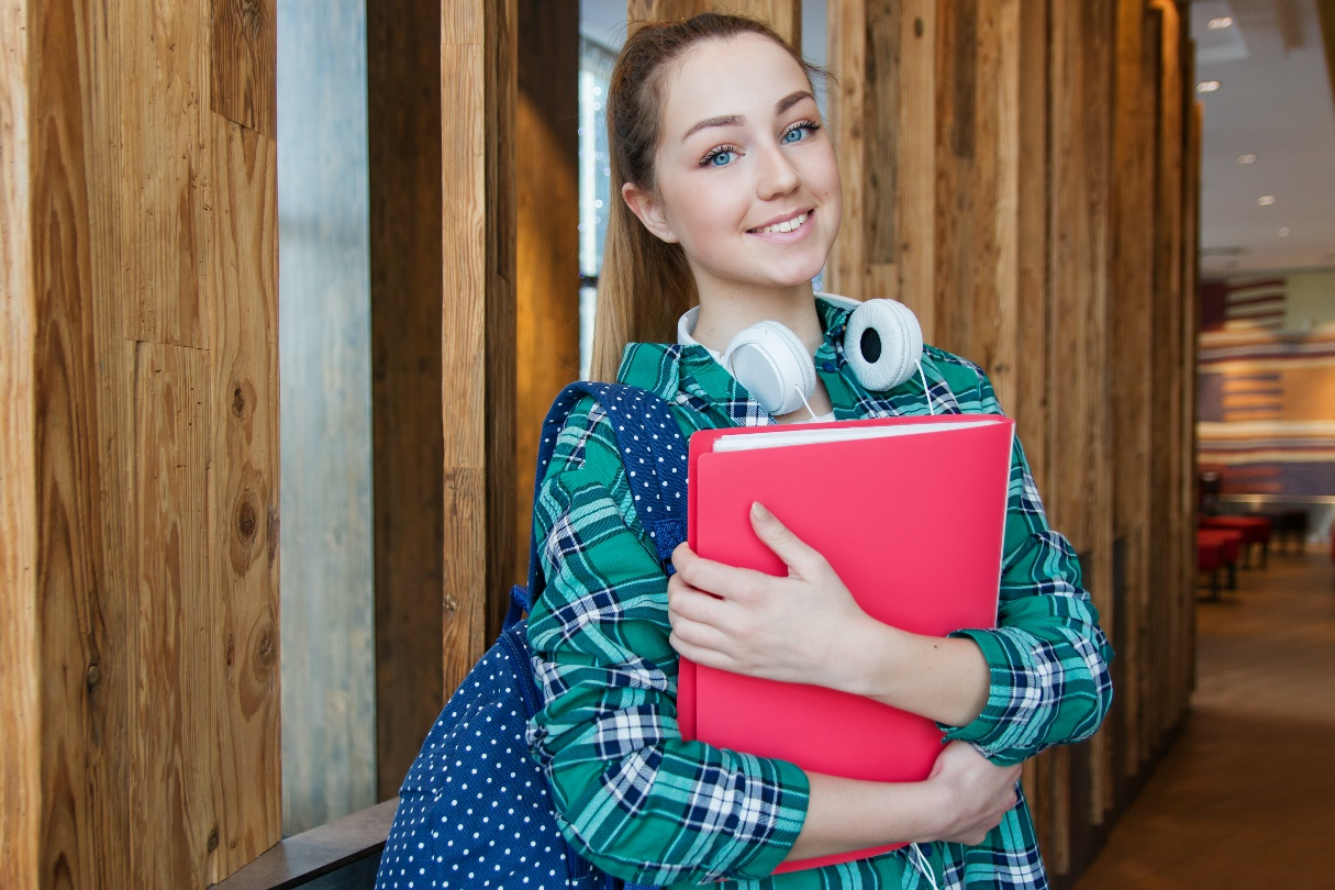 A student wearing headphones and holding a portfolio