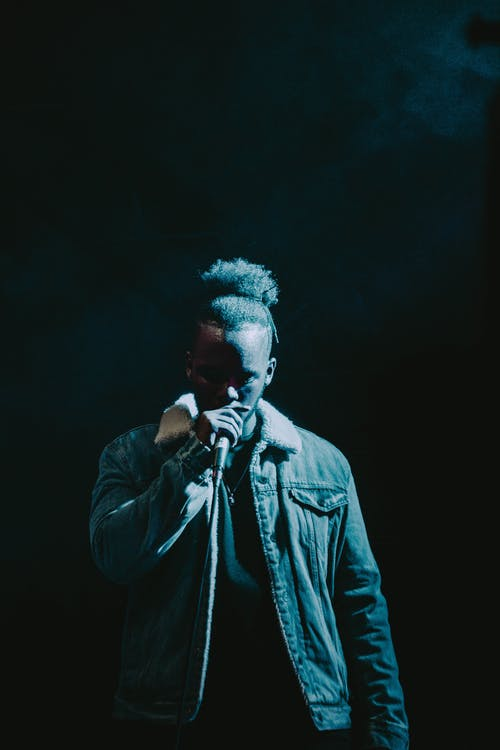 A man singing wearing a denim jacket