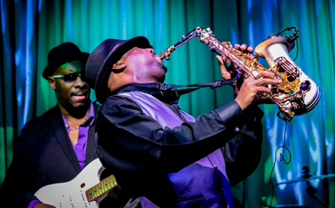 People performing on stage with a saxophone.